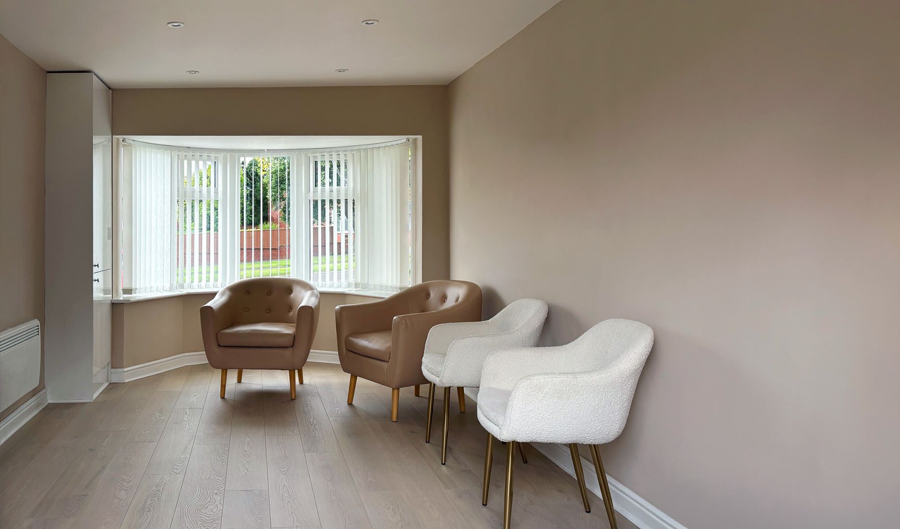 inside of a garage conversion with a pair of white chairs and a pair of brown leather chairs