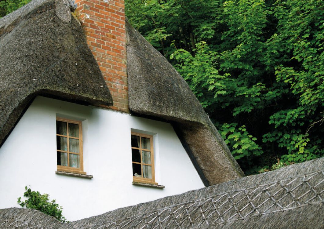 thatched roof cottage with whitewashed walls and Wood effect heritage-style uPVC windows