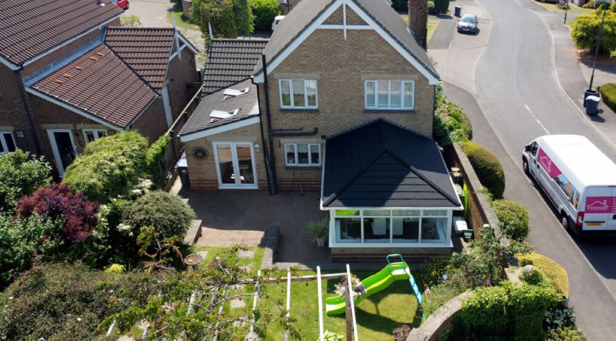 aerial view of back garden with conservatory featuring a newly-installed supalite roof, with a Tyneside Home Improvements van on the right side parked on the roadside