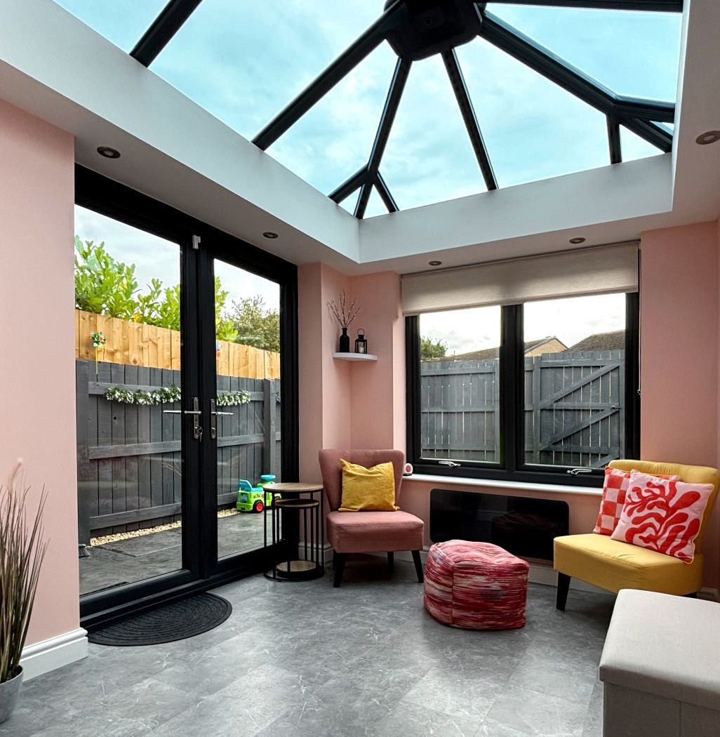 inside view of orangery with light pink walls, plus french doors and glass roof